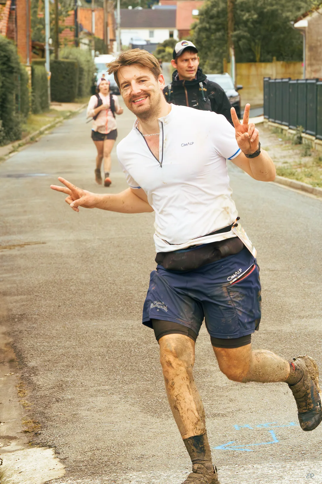 Coureur en plein trail faisant un signe de victoire, photo lifestyle sportive