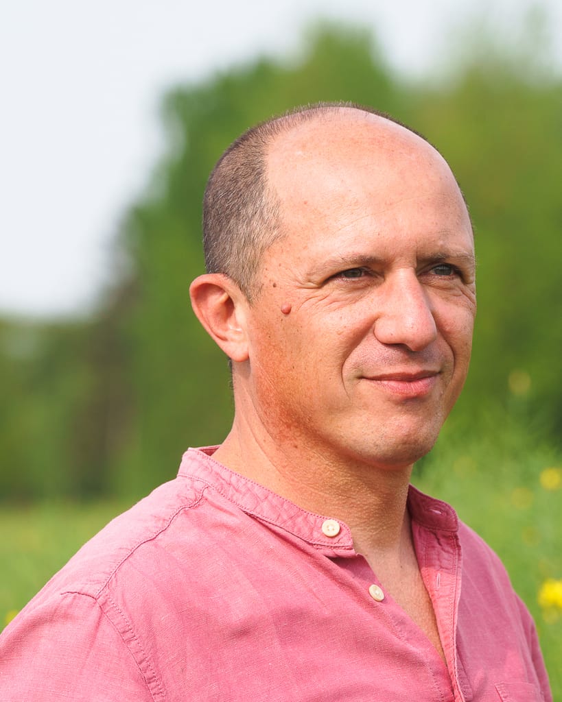 Portrait professionnel d’un homme en extérieur, lumière naturelle et regard détendu.